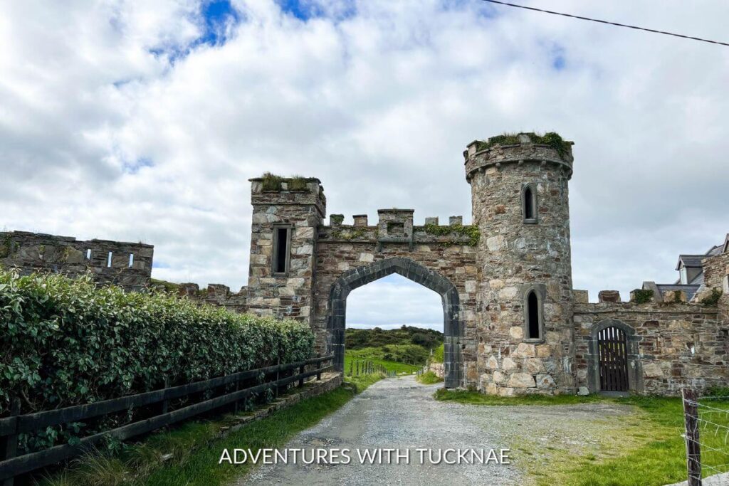 The entrance gate to Clifden Castle. There is a turret on each side of the road with an archway connecting the two.