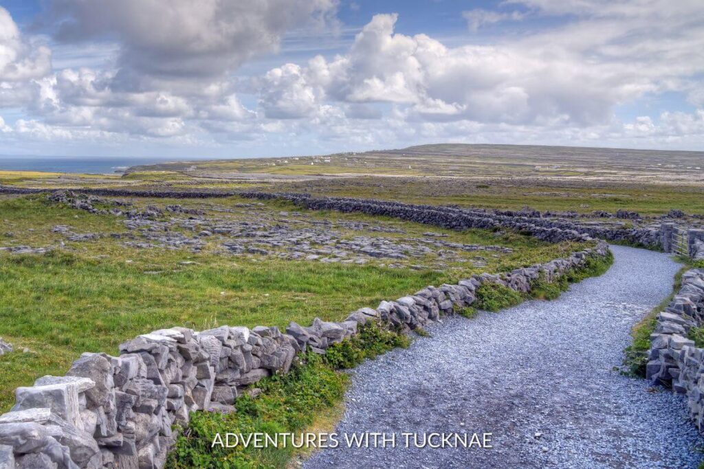 A path through Inishmore in the Aran Islands of Ireland. The path is lined with short stone walls winding through the Irish countryside. 