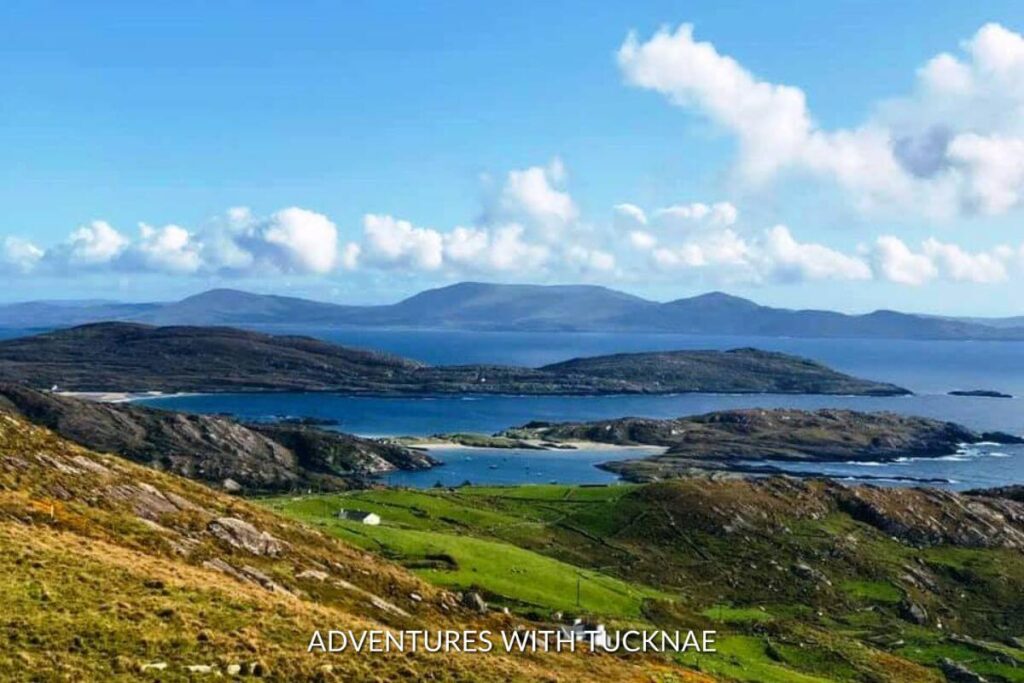 A beautiful view of the Ring of Kerry in Ireland during a weekend break in Ireland. The sea is visible in the distance, surrounded by mountains, islands, and Irish countryside. 