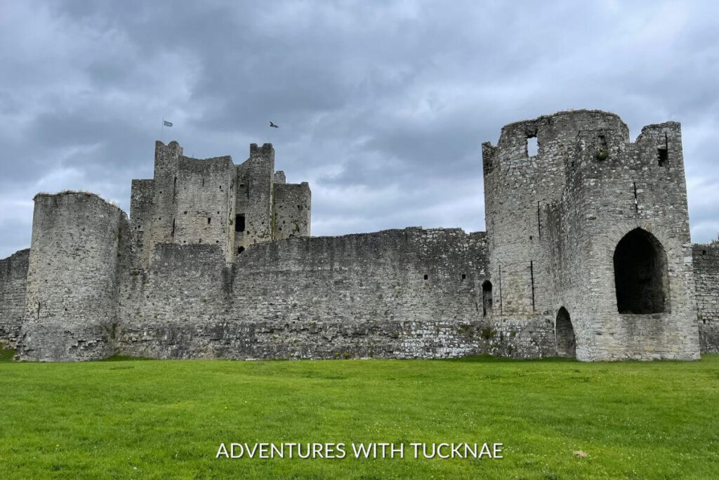 The stone ruins of Trim Castle in Trim Ireland. The castle ruins are grey and run down with a keep flying two flags visible in the background. 