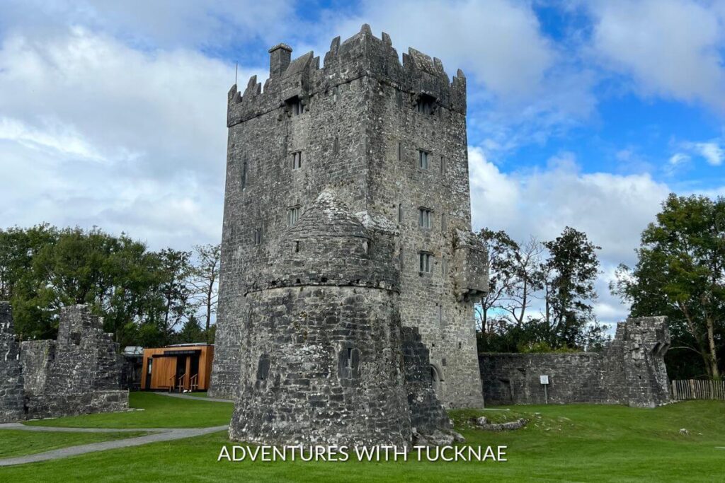 View of Aughnanure Castle from below. The castle has both square and round towers. This stone castle is surrounded by lush green grass
