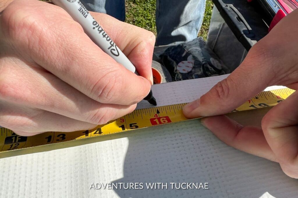 Using a tape measure and sharpie to mark where we need to cut the vinyl for our RV skirting 