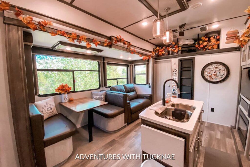The living room slide in our RV with Fall RV decor including fall leaf garland above the slide and a vase with fall foliage on the table.