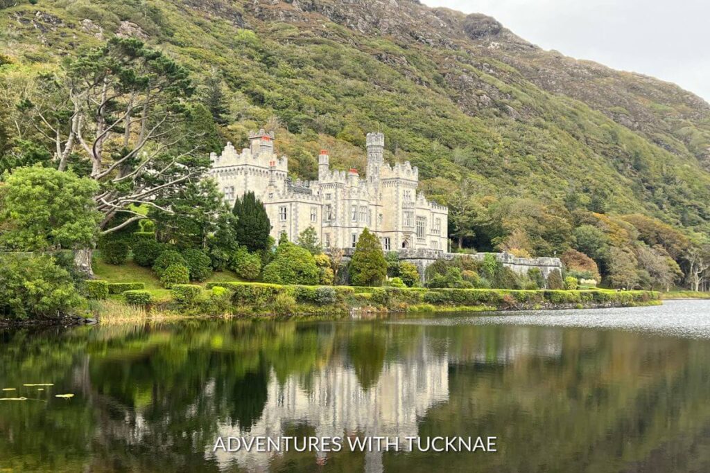 Kylemore Abbey castle in county Galway reflecting in the lake, surrounded by lush green foilage