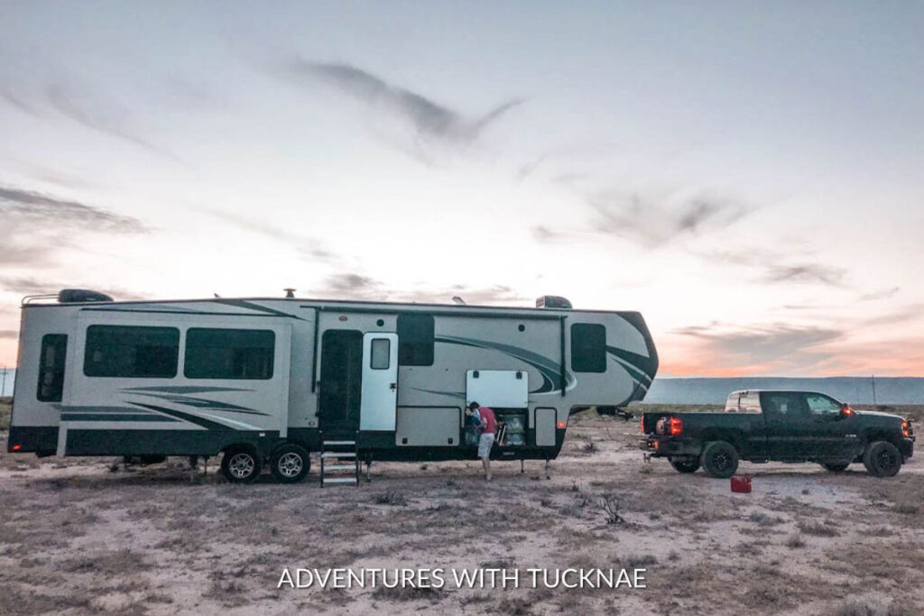 Fifth wheel and truck boondocking in the desert. The sun is setting and the sky is colorful and gorgeous