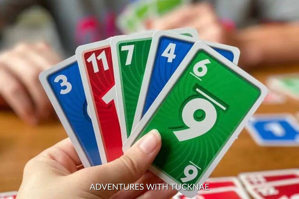 Playing Skip-bo in our RV showing the hand of cards including a blue 3, red 11, green 7, blue 4, and green 6.