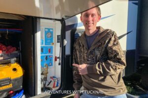 Tucker pointing to our new ABCO RV water panel in our fifth wheel RV storage bay.