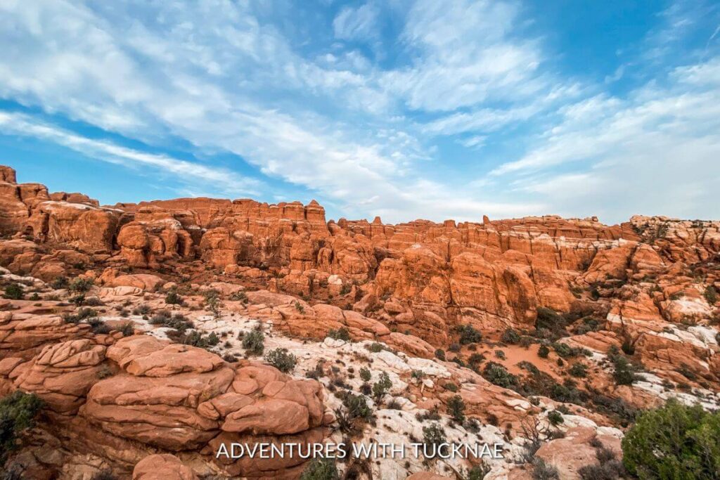 A view of the Fiery Furnace Trail in Arches National Park. The landscape is fiery orange and red, and the rock formations are unique. 