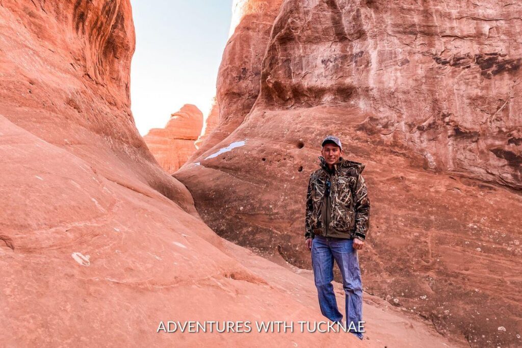 A man hiking in a camouflage coat and jeans in Arches National Park.