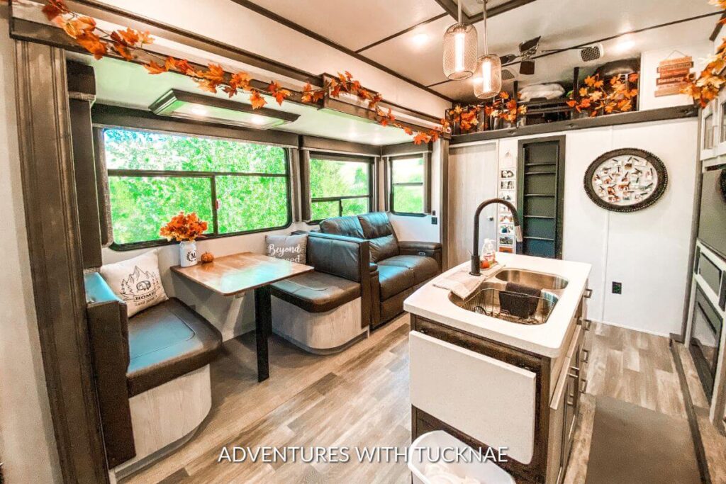 An RV living space and kitchen, decorated for Fall with leaf garland and other Fall decorations.