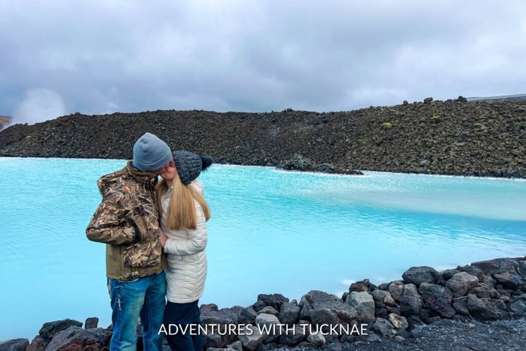 A couple standing and kissing in front of Blue Lagoon in Iceland