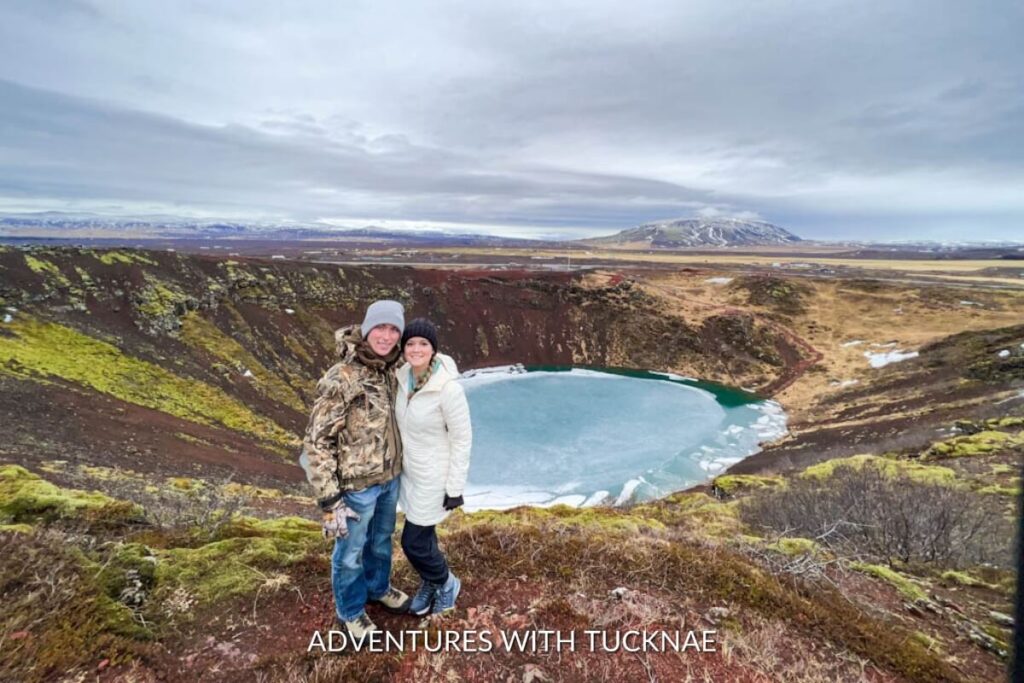 A couple posing for a picture in front of Kerið Crater in Iceland