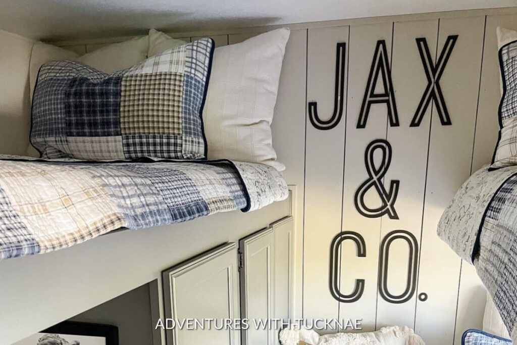 A light green kids bunk room with letters on the wall spelling out "JAX & CO."