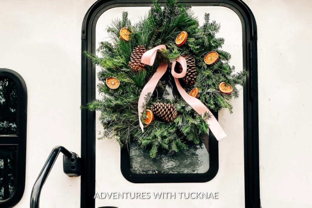 A pretty Christmas wreath with pine cones and orange slices on an RV door