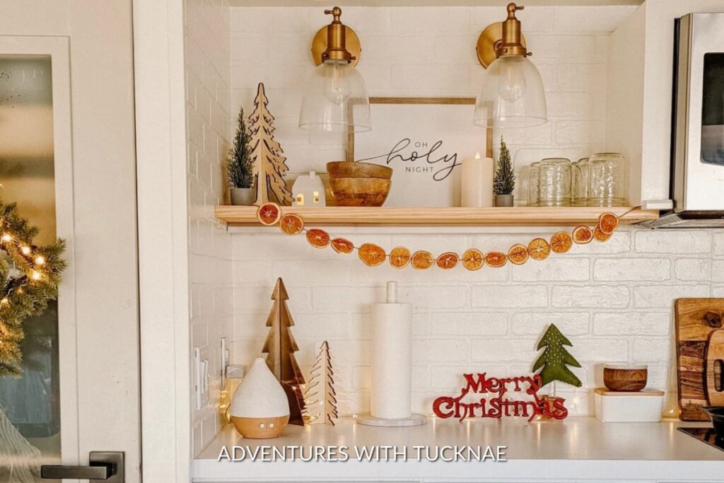A beautifully decorated RV kitchen ready for Christmas with holiday signs and orange garland