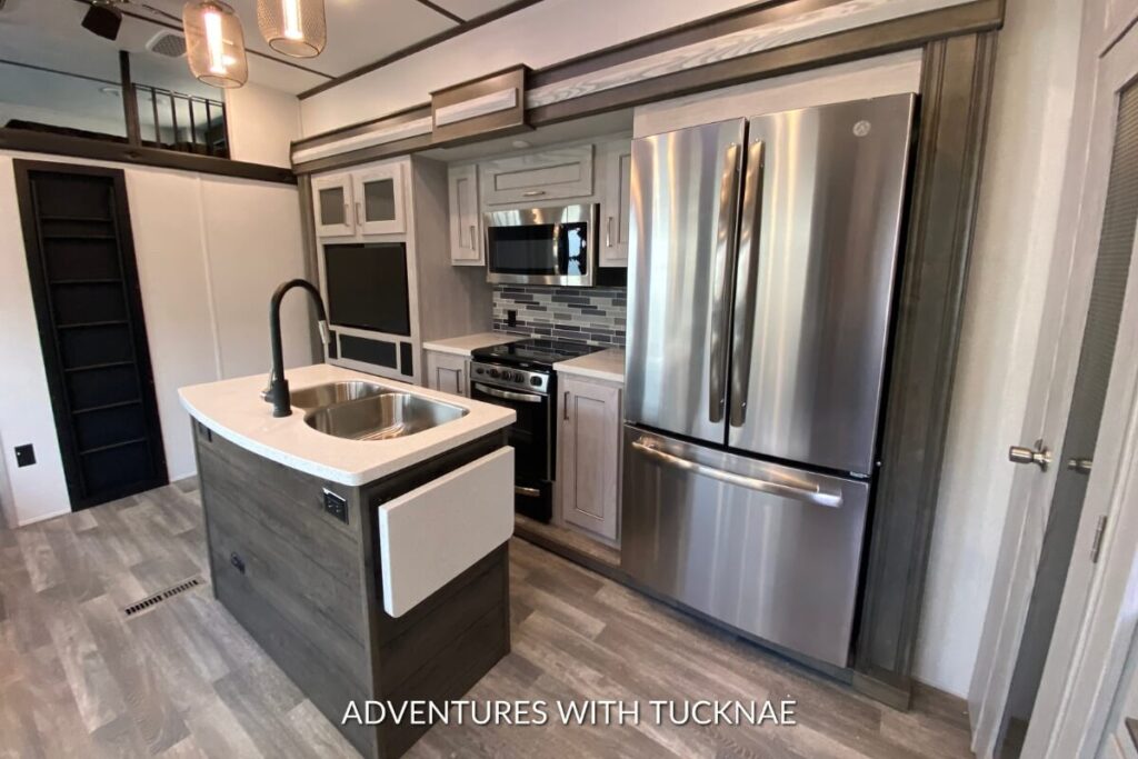 An RV kitchen in a fifth wheel with a large refrigerator, microwave, and kitchen island