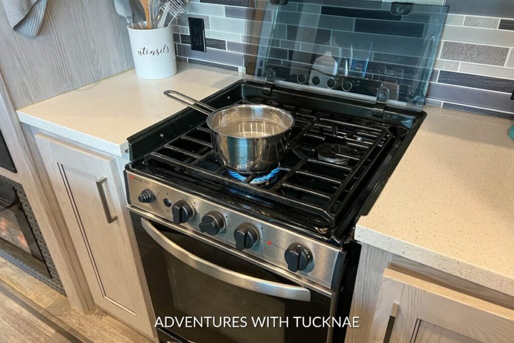 A pot of water boiling on the stovetop in an RV kitchen