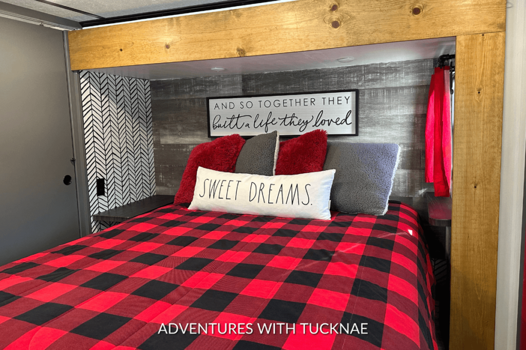 A mattress in an RV bedroom with red, black, and white renovations and decor.