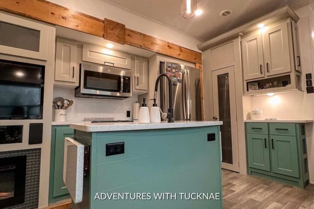 A renovated RV kitchen with grey and green painted cabinets and new slide trim