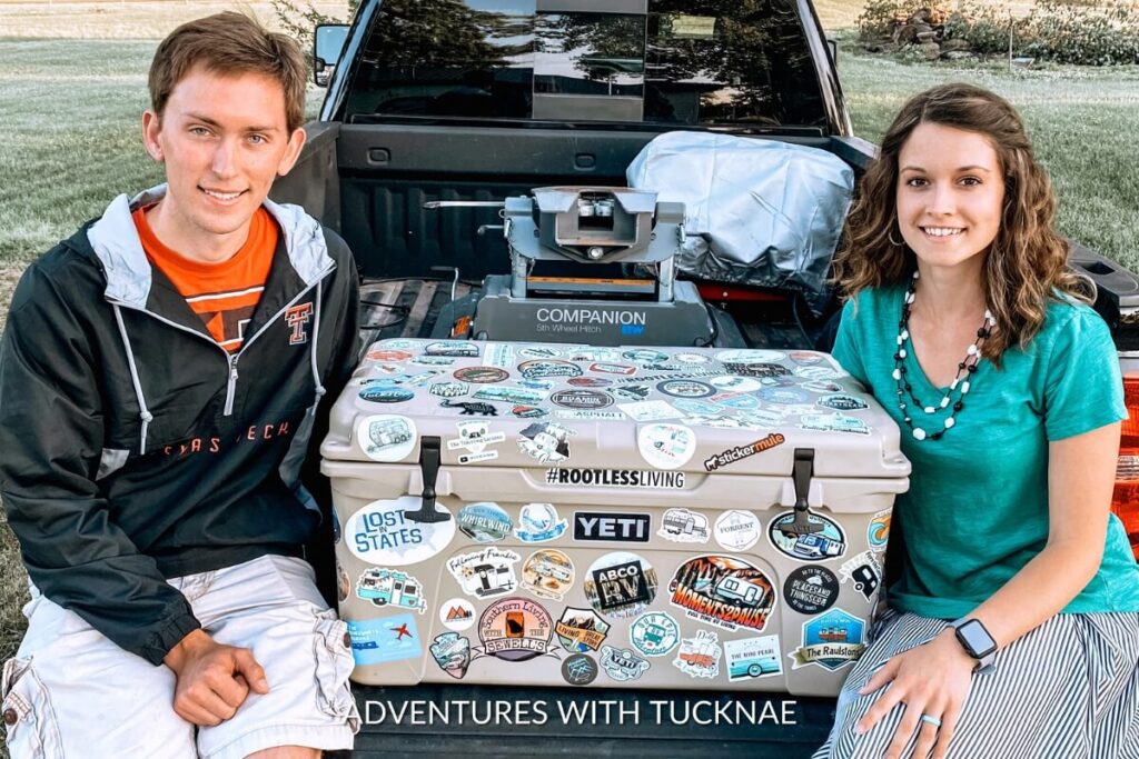 A couple sitting by their Yeti cooler covered in RV Stickers