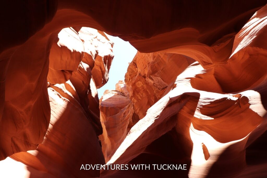 Sunlight filters through the narrow opening of Antelope Canyon X, illuminating the smooth, flowing lines of the orange sandstone canyon walls.