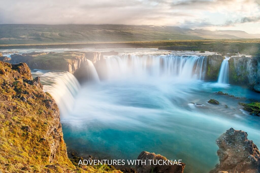 Goðafoss, illuminated by the soft light of dawn, showcases the serene flow of water, a must-see destination among the best waterfalls in Iceland.