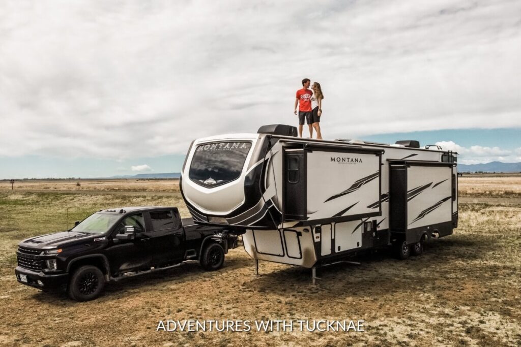 A couple standing on top of their Keystone Montana High Country 335BH RV while boondocking
