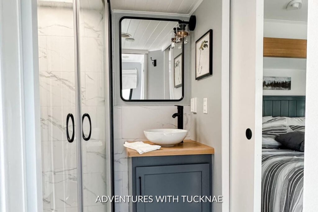 A sleek and modern RV bathroom renovation with black and white accents and a blue painted cabinet
