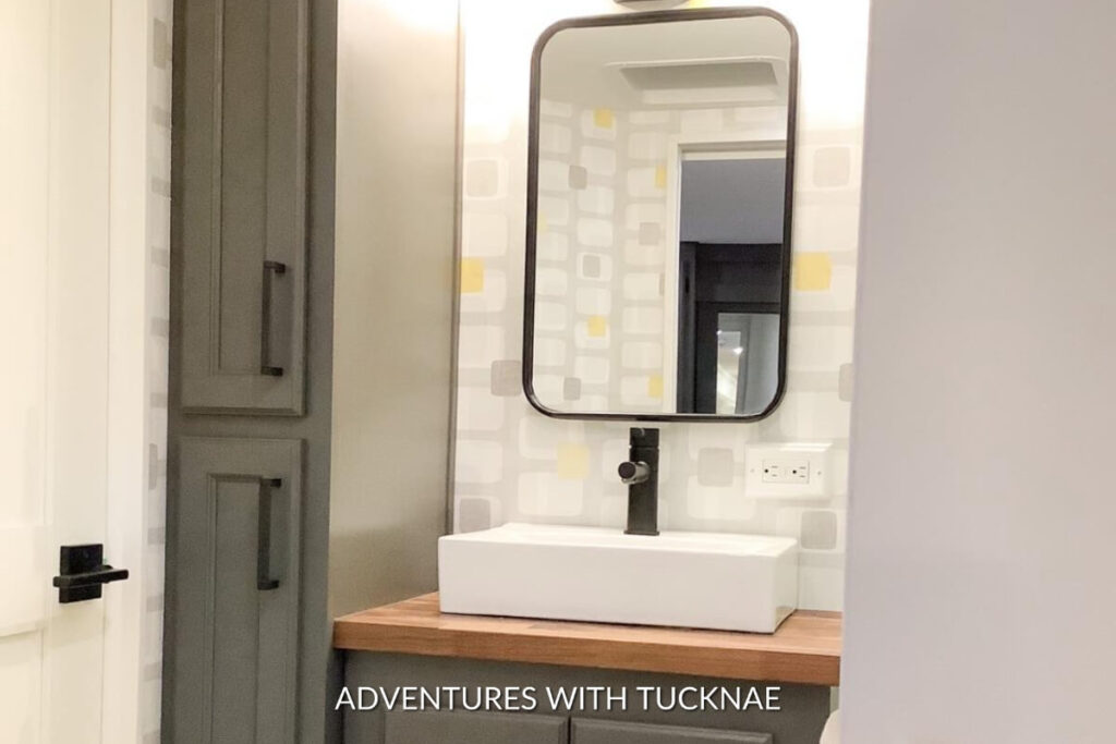 An RV bathroom remodel with yellow and grey wallpaper and a new sink
