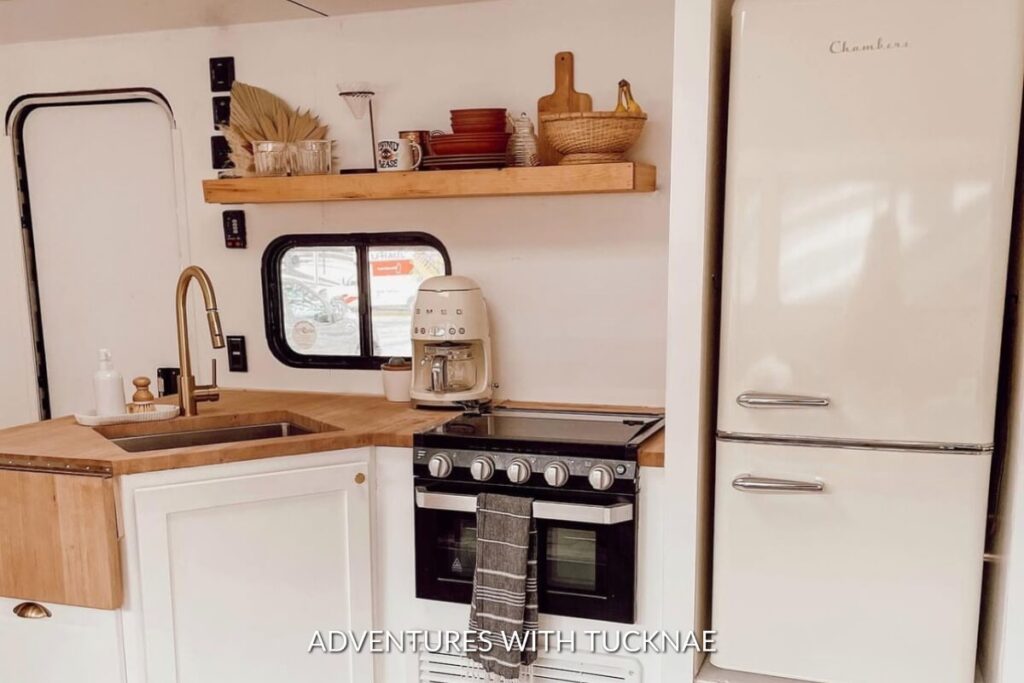 Charming RV kitchen with a vintage-style cream refrigerator, wooden countertops, and a coffee machine on the counter.