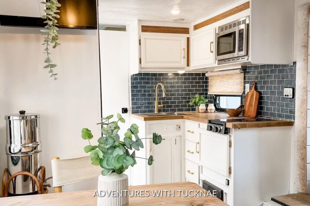 Compact RV kitchen corner with subway tile backsplash, a steel sink filled with fresh produce, and a cutting board.