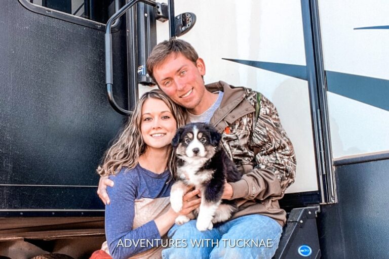 A couple with their Mini Aussie puppy in front of their RV