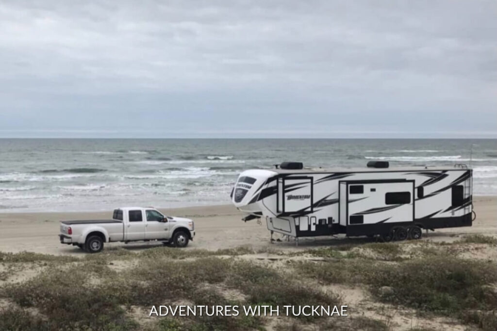 A large fifth wheel RV boondocking on the beach by the water 