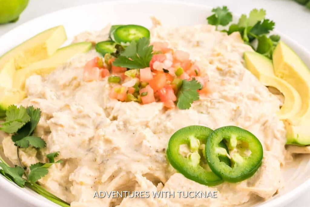 Creamy crock pot green chile chicken with avocado slices, a comforting meal that's perfect for RV camping cuisine.