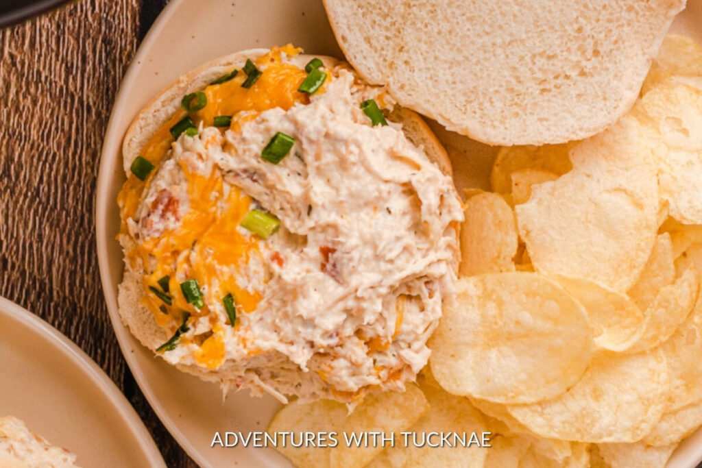 Delicious RV camping crockpot meal of crack chicken, creamy and cheesy, garnished with green onions, served alongside crispy chips.