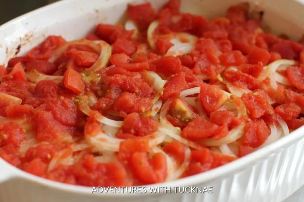Layers of sliced potatoes and onions topped with tomato chunks, showcasing a hearty rv camping crockpot meal for a comforting shipwreck casserole.