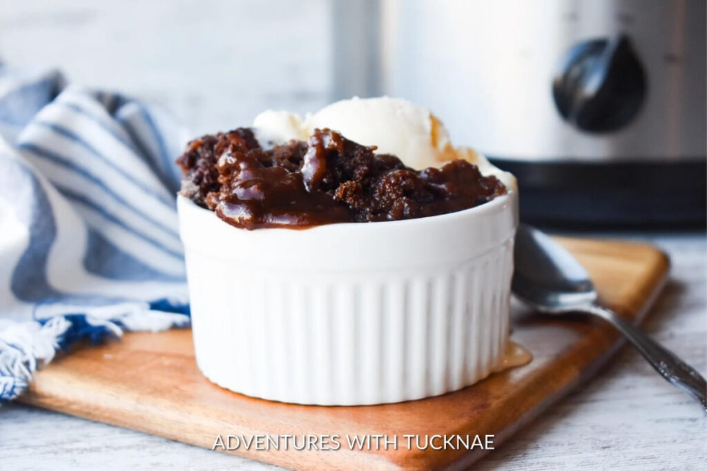 Crock Pot Chocolate Cobbler in a white ramekin, with rich, gooey chocolate underneath a layer of melted ice cream, suggesting a decadent dessert.