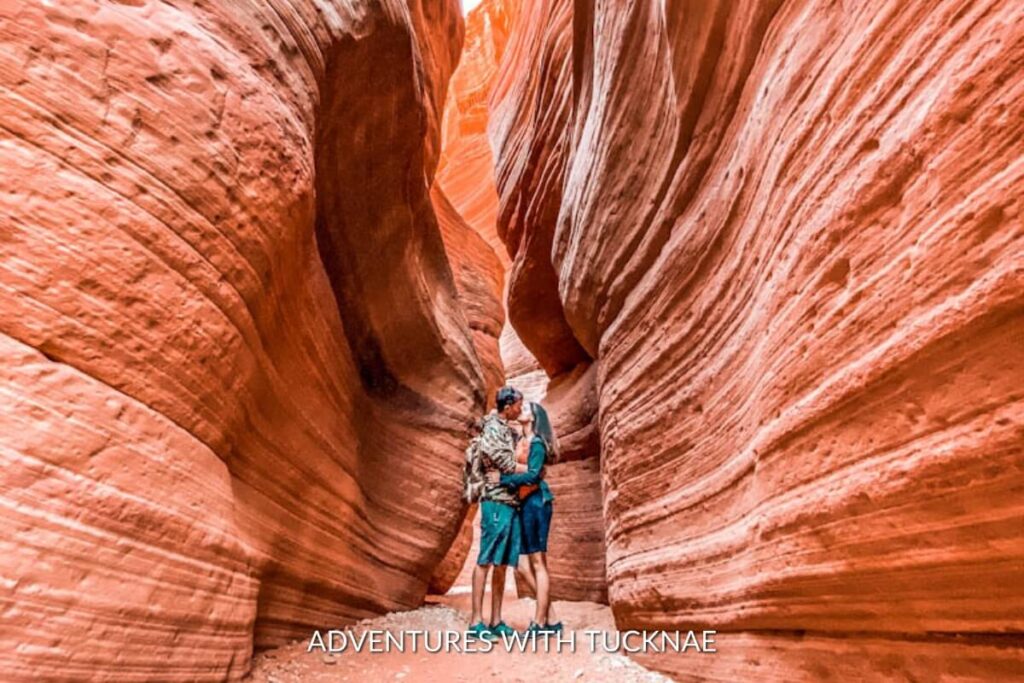 A couple shares a romantic moment in Peekaboo Slot Canyon, where the smooth, undulating walls create a secluded and instagrammable scene in Utah's desert.