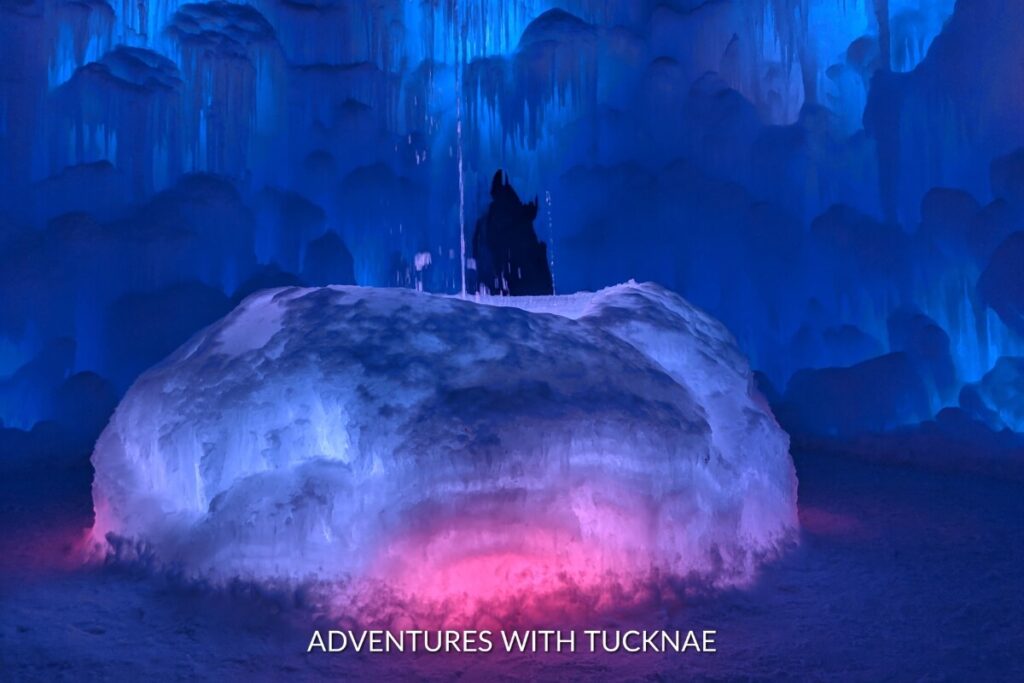 A magical scene at the Ice Castles, with a silhouetted figure against the glowing blue ice, creating an ethereal and instagrammable winter wonderland in Utah.