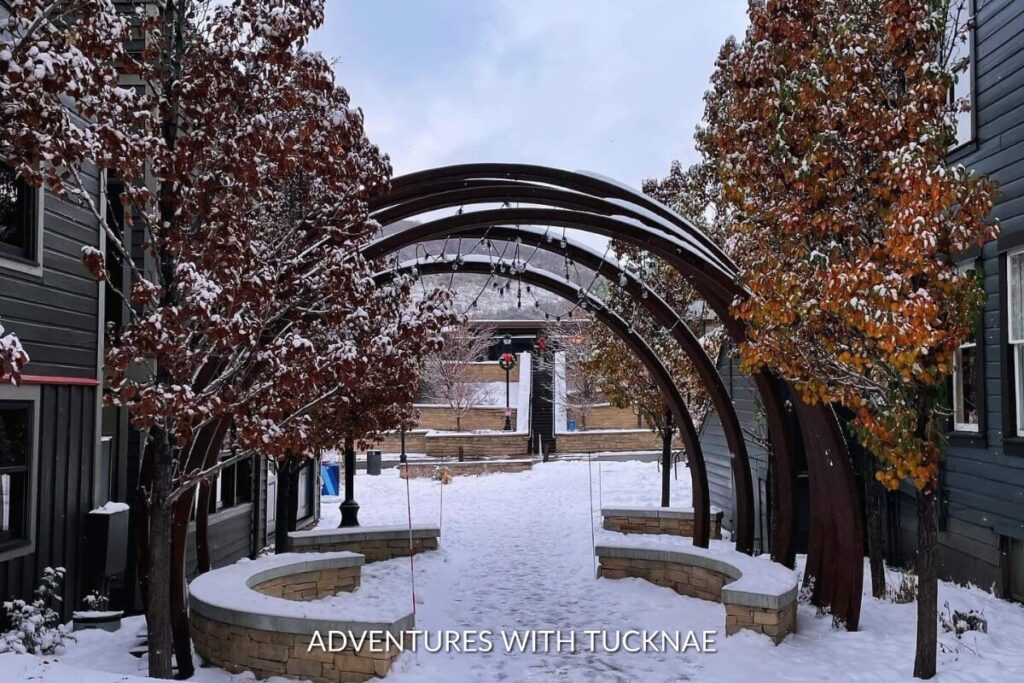 A winter wonderland archway in Park City, Utah, adorned with snow-covered branches and festive decorations, creating an enchanting, instagrammable scene.