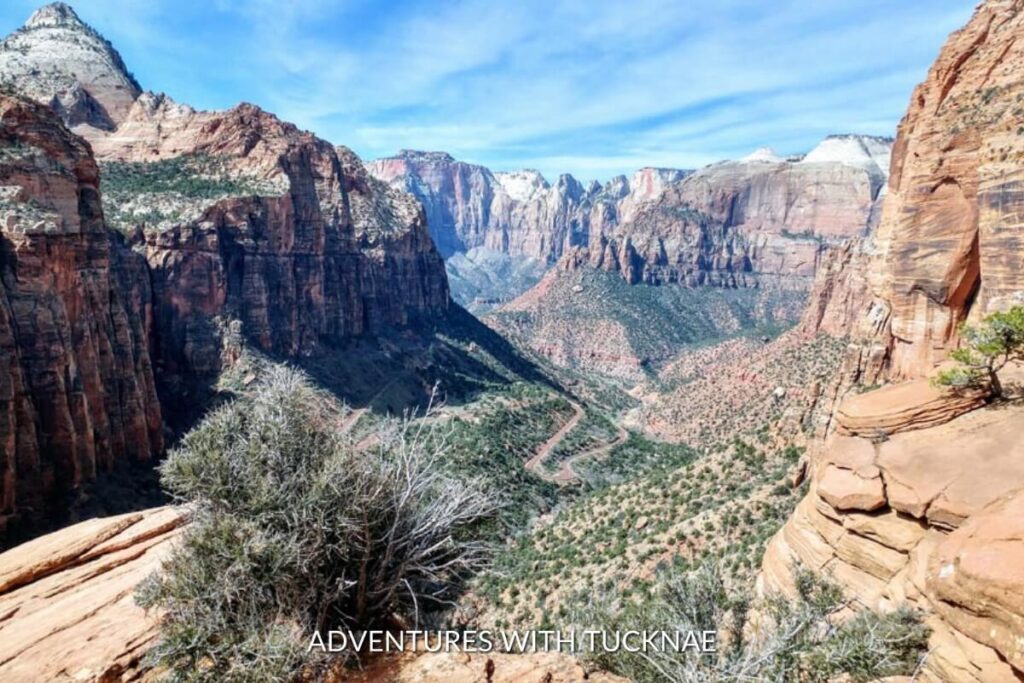 The Canyon Overlook Trail, an instagrammable path in Zion National Park, Utah, offers a stunning vista of rugged landscapes and towering rock formations under a cloud-streaked sky.