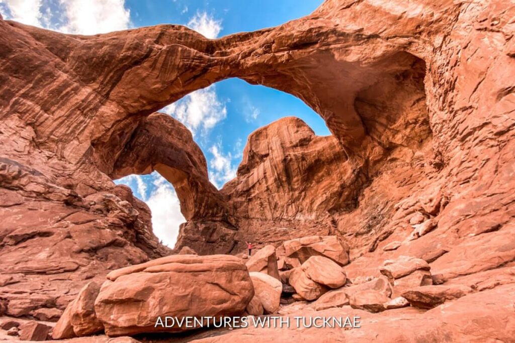The magnificent Double Arch, a unique and instagrammable geological feature in Arches National Park, Utah, showcases two interconnected arches against a bright blue sky.