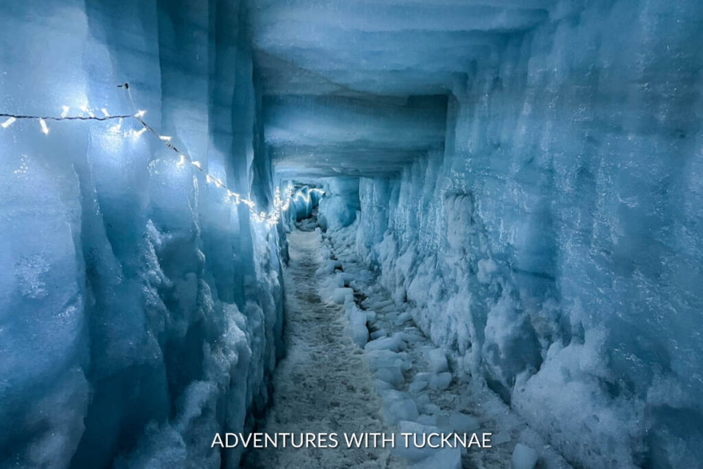 Illuminated ice tunnel pathway at Into the Glacier, revealing the stunning blue hues and textured walls of the glacial interior.