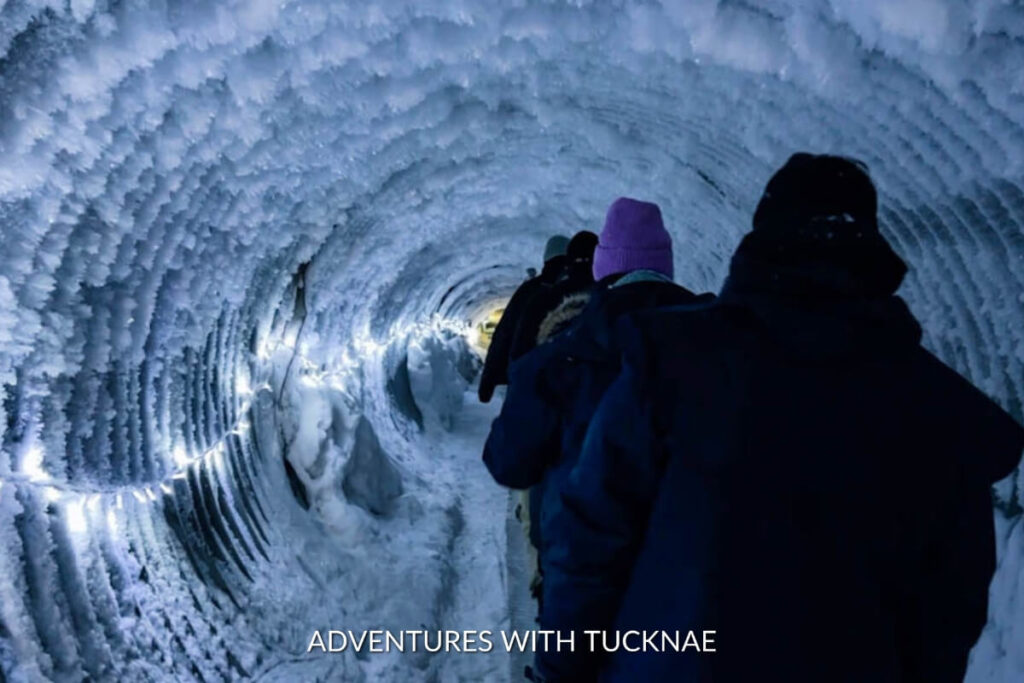 Group of visitors walking through a spiral ice tunnel at Into the Glacier, with the walls displaying unique ice formations.