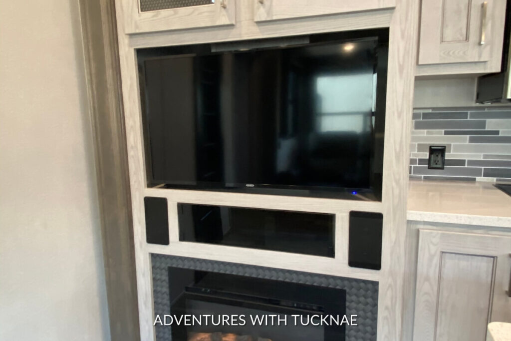 Close-up of an entertainment center with a flat-screen TV and fireplace in a Keystone Montana High Country RV.