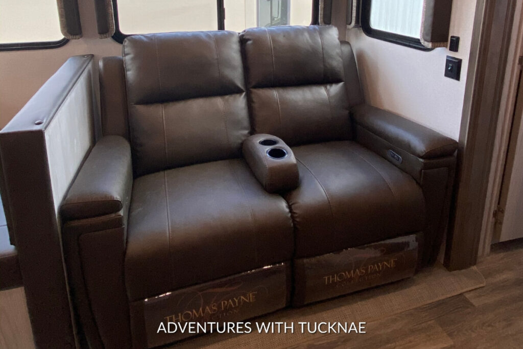 Comfortable RV seating area with a brown leather Thomas Payne recliner and cup holders in a Keystone Montana RV.
