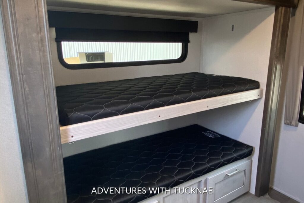 Stacked bunk beds in a well-lit room of a Keystone Montana High Country RV.