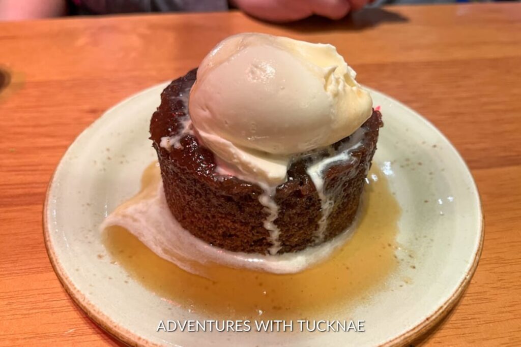Warm sticky toffee pudding crowned with a melting scoop of vanilla ice cream, served on a ceramic dish as a sumptuous dessert in Las Vegas.