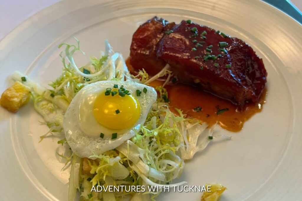 Succulent pork belly with crispy skin, served with frisée and a perfectly cooked sunny-side-up egg, a gourmet dish in Las Vegas.
