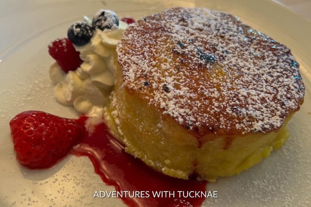 A warm creme brulee french toast topped with whipped cream and fresh berries, drizzled with berry sauce, a zesty dessert option in Las Vegas.